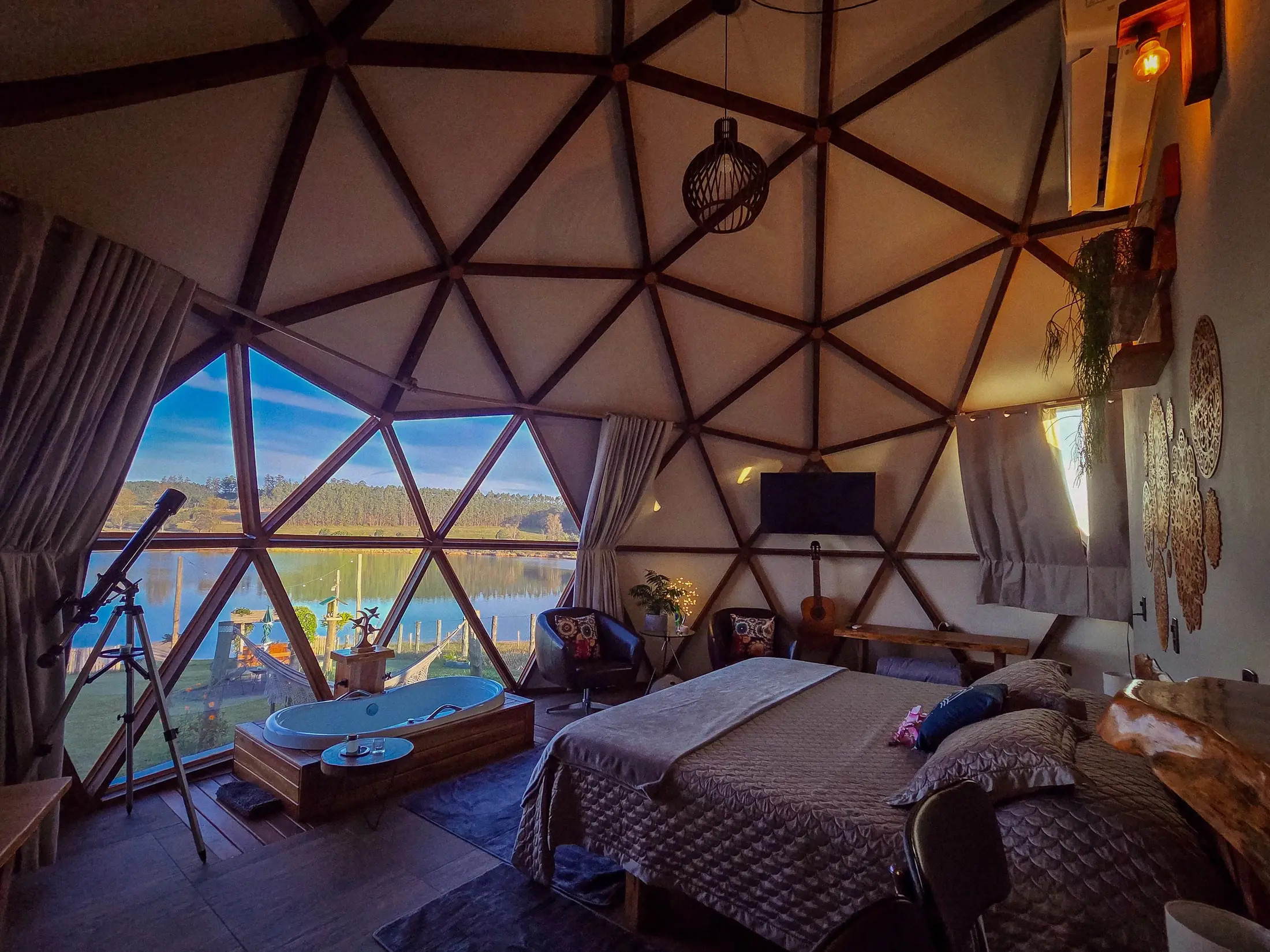 O interior do domo: a cama king, o ofurô e a janela panorâmica para a represa