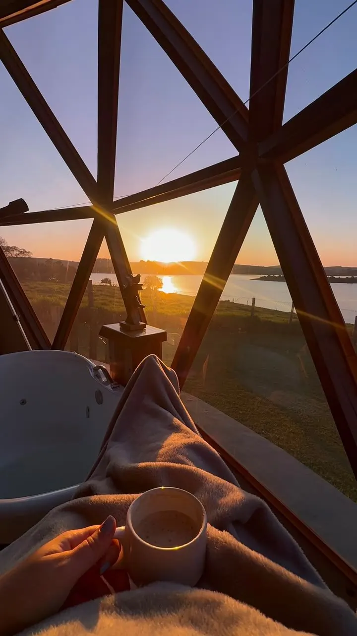 O sol se pondo sobre a represa, visto entre as hastes da cúpula